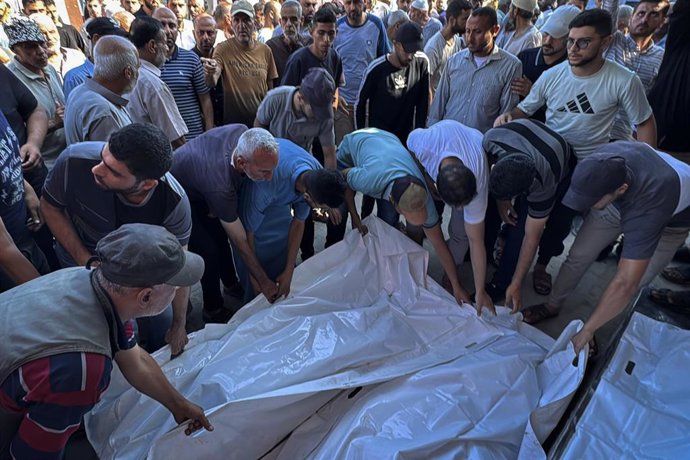 Palestinos junto a varios muertos por los ataques del Ejército de Israel contra Deir al Balá, en el centro de la Franja de Gaza