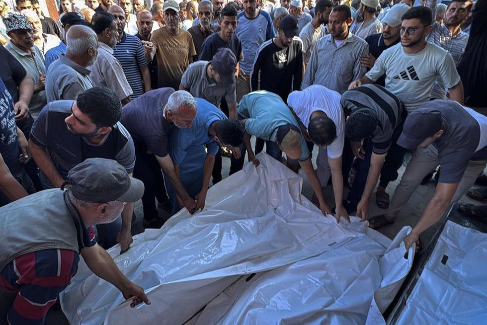 Palestinos junto a varios muertos por los ataques del Ejército de Israel contra Deir al Balá, en el centro de la Franja de Gaza