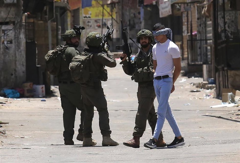 Militares israelíes detienen a un joven palestino.