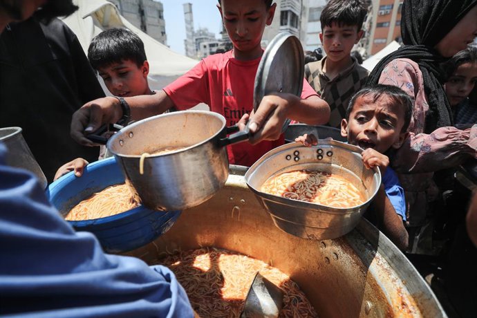 June 21, 2025, Gaza City, Gaza Strip, Palestinian Territory: Palestinians wait in long queues to receive pots of food distributed by charitable organizations, in Gaza city, on June 21, 2025