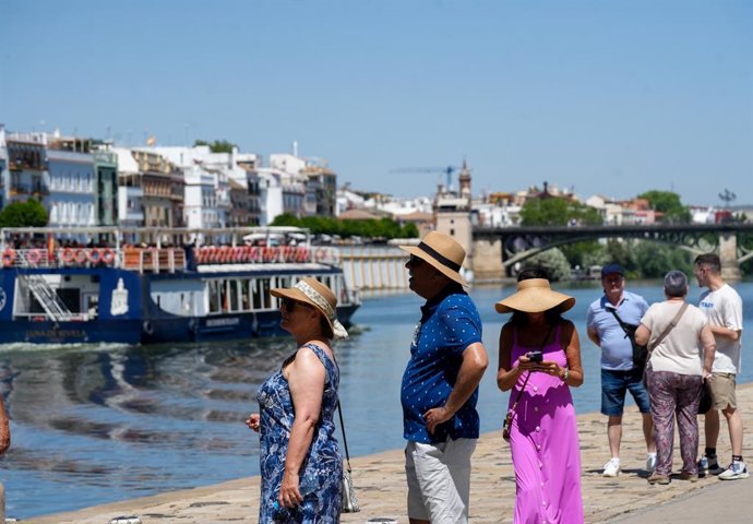 Personas con ropa veraniega paseando junto al río. A 28 de mayo de 2025, en Sevilla (Andalucía, España)