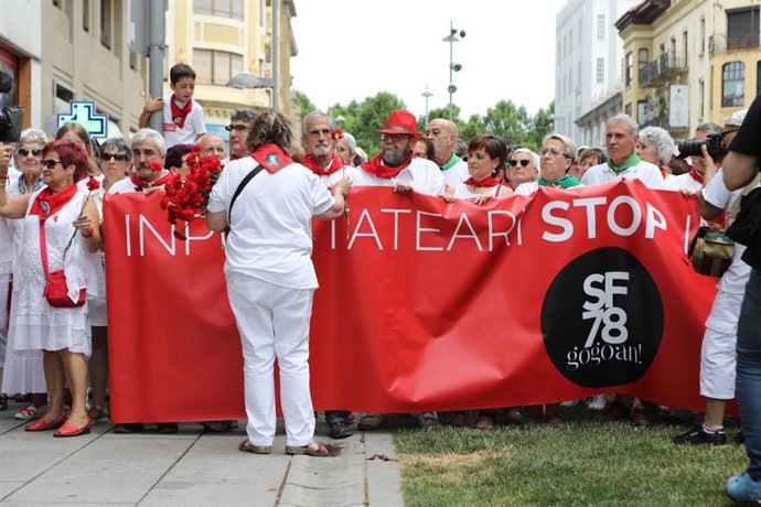 Archivo - Una mujer reparte claveles rojos a los asistentes al homenaje a Germán Rodríguez, fallecido por disparos de la policía en los Sanfermines de 1978 en Pamplona.