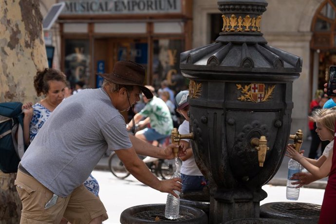 Archivo - Varias personas se refrescan y rellenan sus botellas de agua en la fuente de Canaletas en una imagen de archivo
