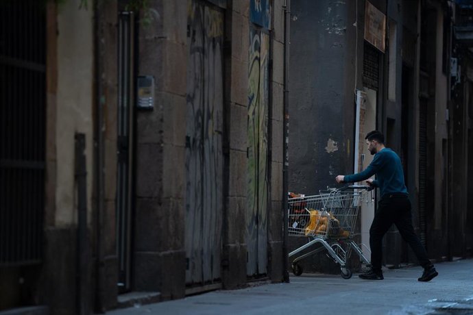 Archivo - Un hombre camina con un carro por una calle céntrica, a 24 de enero de 2024, en Barcelona, Catalunya (España). 