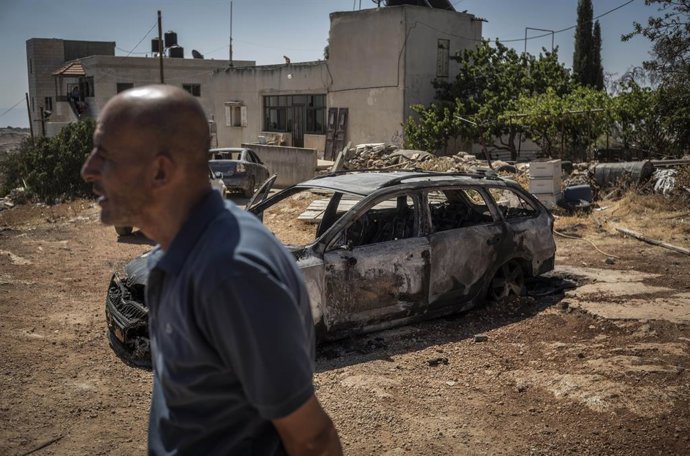 26 June 2025, Palestinian Territories, Kafr Malik: 26 June 2025,West-Bank,Kufr-Malik: A Palestinian man walks by a destroyed vehicle following an attack by Israeli right-wing settlers and intervention by the Israeli military attackin the West Bank village