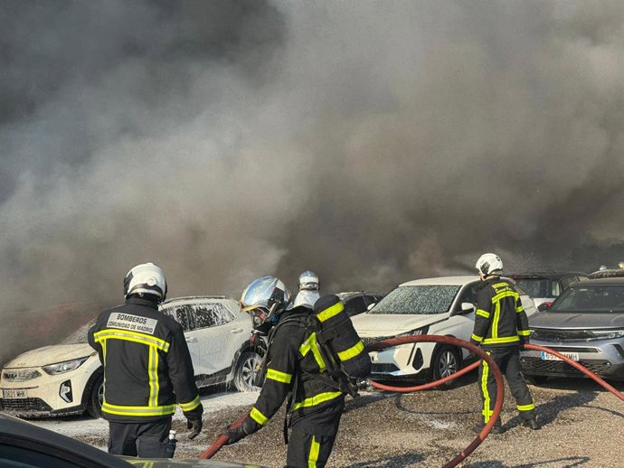 Os bombeiros tentam apagar um incêndio que afeta um estacionamento com mais de 100 veículos estacionados.