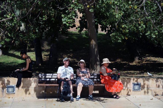 Varias personas se protegen del sol en una calle de Málaga. A 27 de junio de 2025, en Málaga (Andalucía, España).