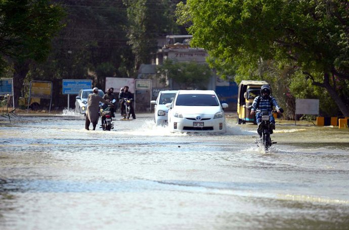 Archivo - April 29, 2025, Pakistan: KARACHI, PAKISTAN, APR 29: Commuters are passing through inundated road by .overflowing drinking water after bursting drinking water lines, creating problems for commuters, .showing negligence of concerned authorities, 