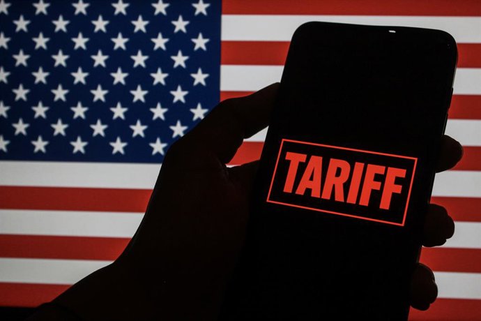 Archivo - April 11, 2025, Indonesia: In this photo illustration, the Tariff text is seen displayed on a smartphone screen with the United States flag in the background.