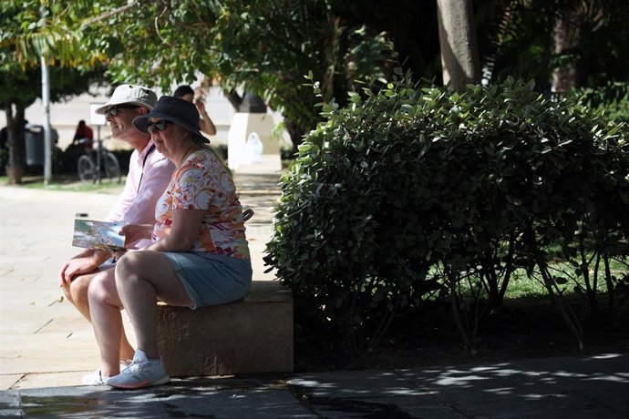 Varias personas se protegen del sol en una calle de Málaga. A 27 de junio de 2025, en Málaga (Andalucía, España). Un total de 22 provincias estarán este viernes en aviso por altas temperaturas en un día en el que la peor parte se la llevará Andalucía, don