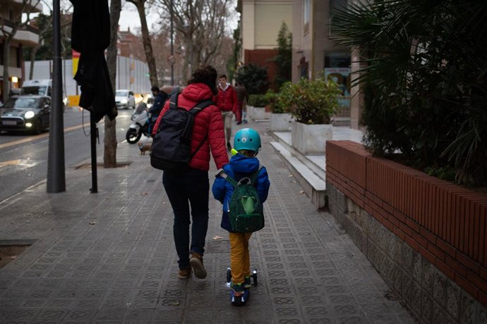 Archivo - Una mujer lleva de la mano a un niño a su primer día de clase presencial tras la Navidad, a 10 de enero de 2022, en Barcelona, Catalunya, (España). Más de 8 millones de alumnos de toda España retoman hoy sus clases tras el periodo vacacional de 