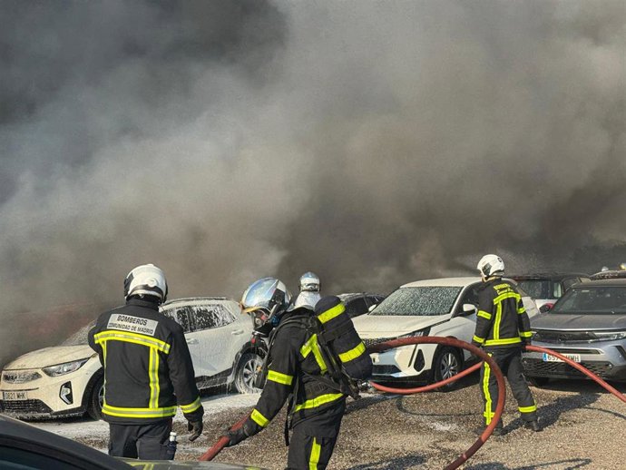 Efectivos de los bomberos tratan de sofocar un incendio que afecta a un aparcamiento con más de 100 vehículos aparcados