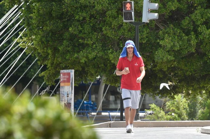 Archivo - Un hombre se cubre la cabeza mientras pasea en una imagen de archivo