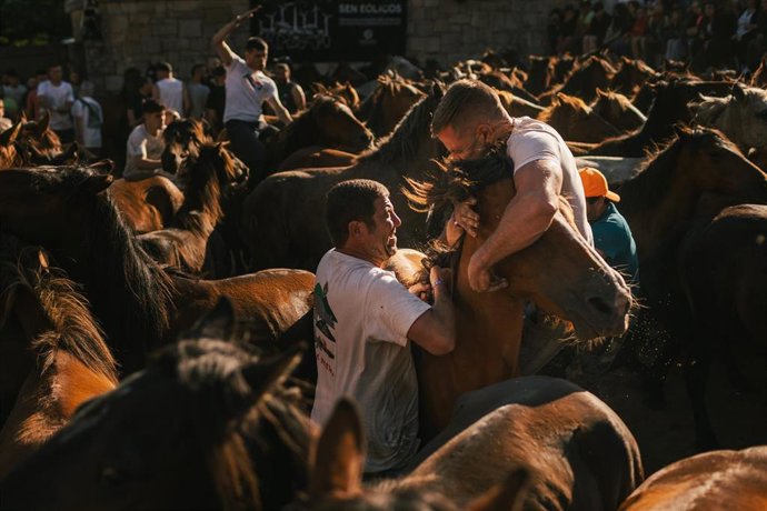 Archivo - Dos hombres sujetan a un caballo durante el primer curro de la Rapa das Bestas 2024, a 6 de julio de 2024, en Sabucedo, Pontevedra, Galicia.
