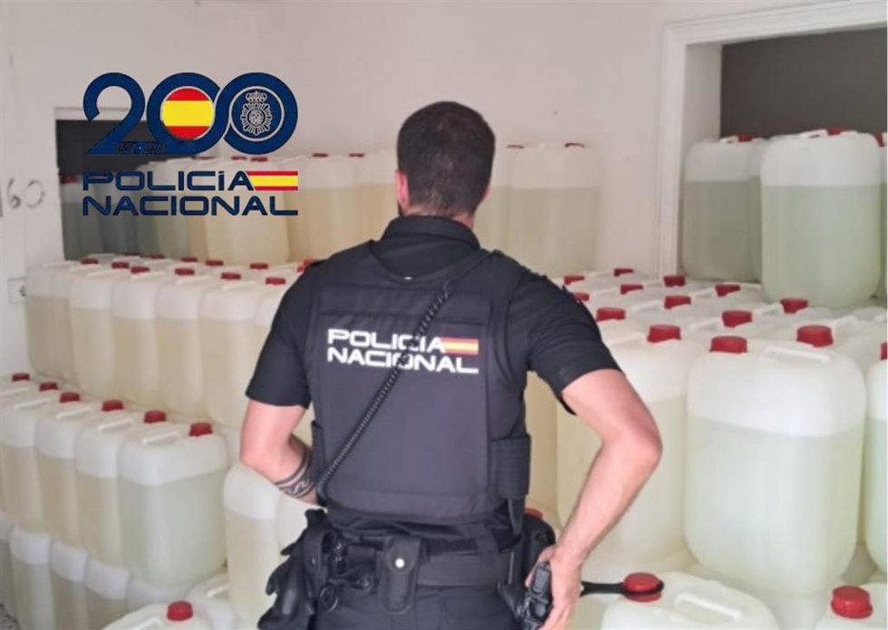 Un agente de la Policía Nacional con las garrafas con combustible para narcolanchas intervenidas en El Puerto.