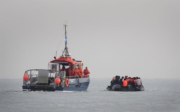 Archivo - Una embarcación francesa vigila a una patera con migrantes