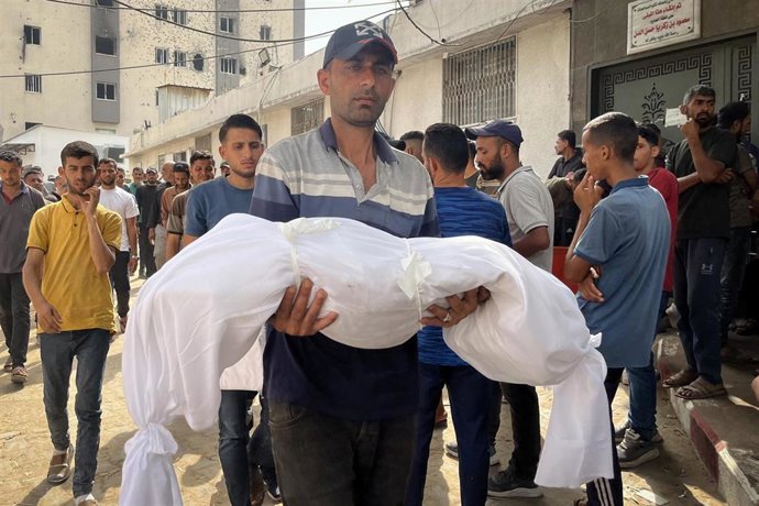 Un ciudadano palestino porta el cadáver de uno de sus familiares muertos en los ataques de Israel.
