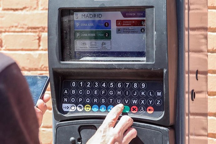 Archivo - Una persona utiliza un parquímetro  