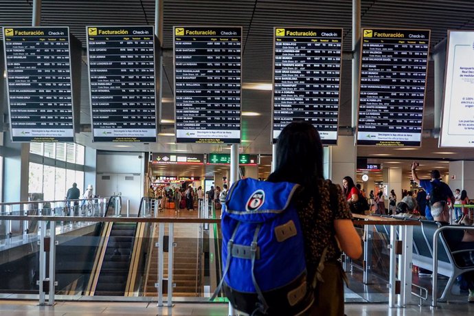 Archivo - Una mujer con una mochila observa los paneles de facturación en el aeropuerto Adolfo Suárez-Madrid Barajas, a 4 de agosto de 2023, en Madrid (España).  