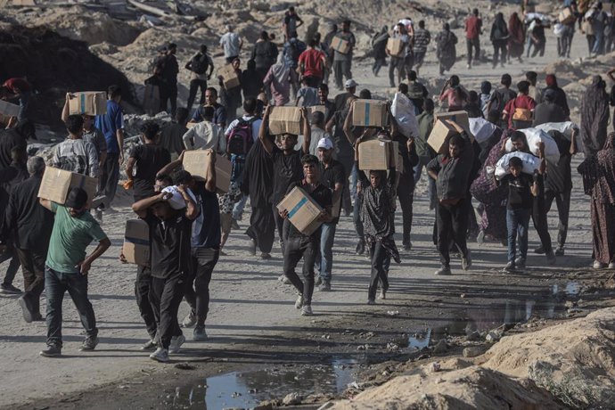 16 de junho de 2025, Territórios Palestinos, Cidade de Gaza: Palestinos carregam pacotes de alimentos, distribuídos pela "Gaza Humanitarian Relief Foundation", enquanto as pessoas lutam contra a fome em meio aos contínuos ataques israelenses à Cidade de G