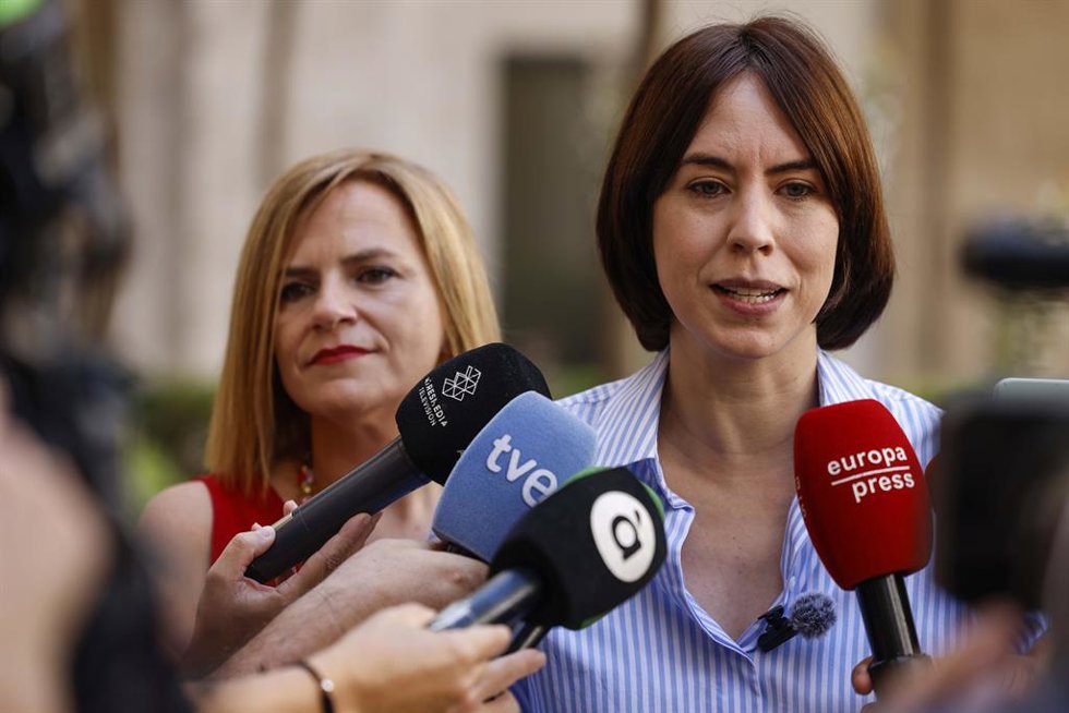 La delegada del Gobierno en la Comunidad Valenciana, Pilar Bernabé (i), y la secretaria general del PSPV-PSOE y ministra de Ciencia, Innovación y Universidades, Diana Morant (d), atienden a los medios de comunicación tras desplegar la bandera LGTBI en l