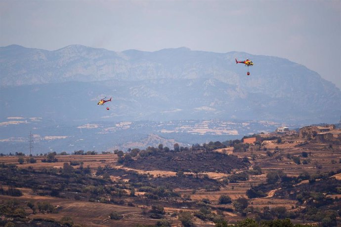 Helicópteros de bomberos tratan de apagar los restos del incendio, a 2 de julio de 2025, en Torrefeta i Florejacs, Lleida.