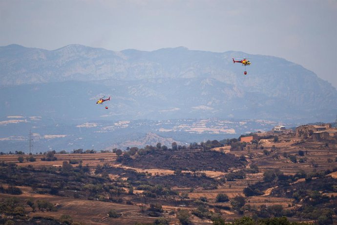 Helicòpters de bombers tracten d'apagar les restes de l'incendi, a 2 de juliol de 2025, a Torrefeta i Florejacs, Lleida.