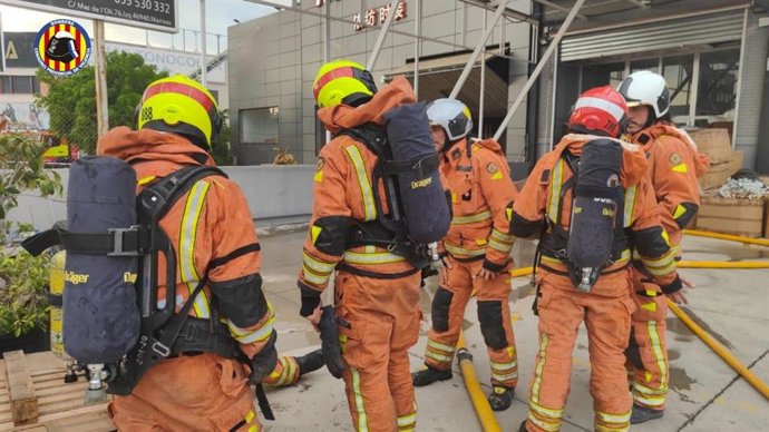Bomberos trabajan en la extinción de un incendio en una nave textil en Manises