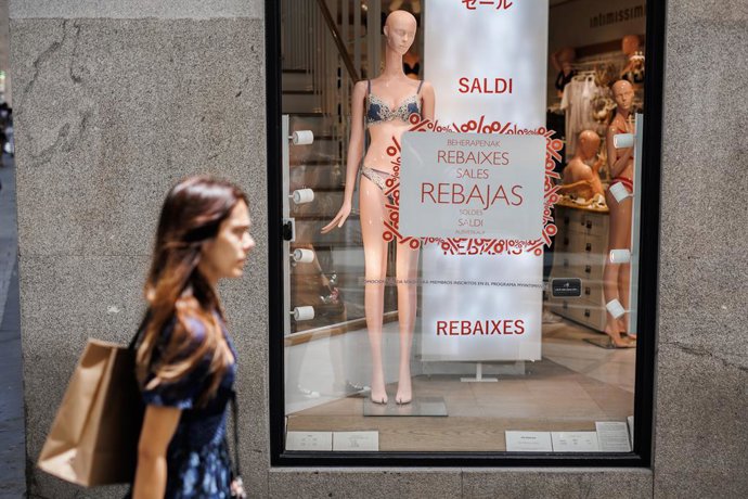 Archivo - Una mujer pasa por el escaparate de una tienda Intimissimi, donde hay colgados carteles para anunciar las rebajas, a 21 de junio de 2022, en Madrid (España). La Comunidad de Madrid comienza el periodo de rebajas de verano 2022 desde este martes,