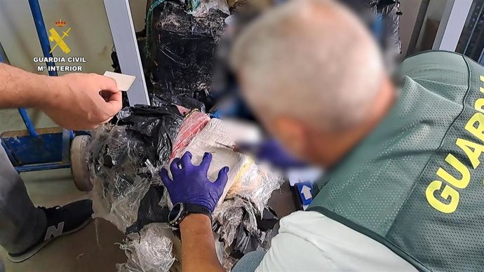 Un agente de la Guardia civil abriendo uno de los fardos de coca incautados en Barbate.