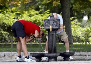 Archivo - Personas refrescándose en una fuente