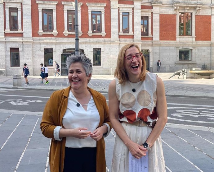 La arquitecta Cristina Colino (i) y la portavoz de Valladolid Toma la Palabra, Rocío Anguita (d), posan tras la fachada del Ayuntamiento de Valladolid