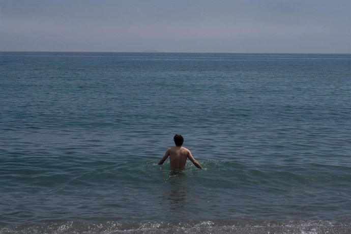 Archivo - Un hombre se da un baño en la playa de la Barceloneta, en una imagen de archivo
