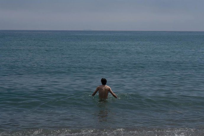 Archivo - Un home banyant-se a la platja de la Barceloneta