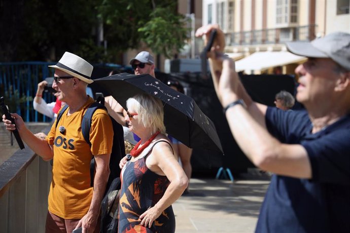 Varias personas se protegen del sol en una calle de Málaga.