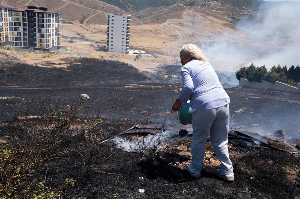 Una mujer intenta extinguir un fuego con un cubo de agua en Esmirna, Turquía