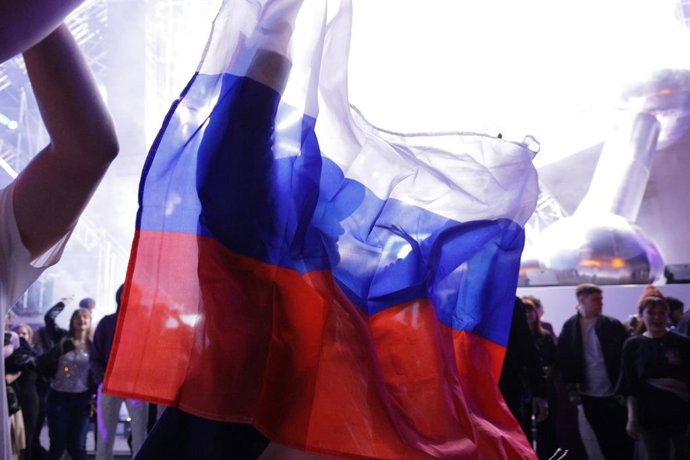 RÚSSIA, MOSCOU - 27 DE JUNHO DE 2025: Um jovem desenrola uma bandeira nacional russa durante uma festa ao ar livre para formandos do ensino médio em VDNkh