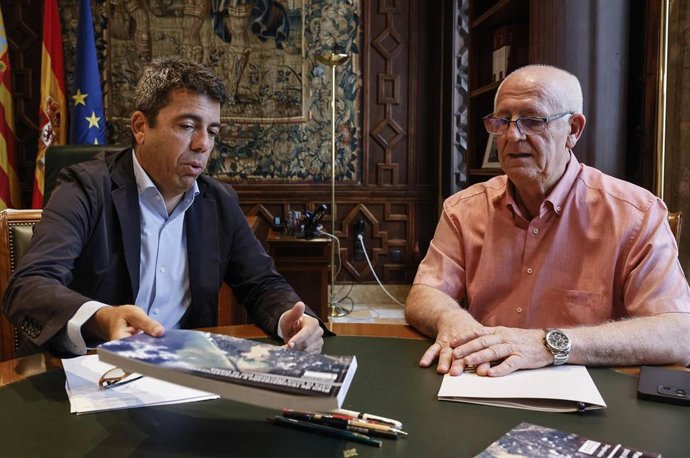El 'president' de la Generalitat, Carlos Mazón (i), muestra el libro del Plan de Recuperación de la dana al nuevo alcalde de Paiporta, Vicent Císcar