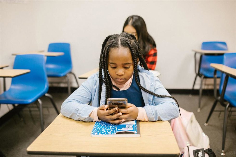 Archivo - Una niña utilizando un 'smartphone' en el aula