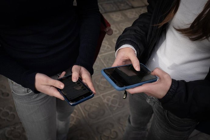 Archivo - Dos personas usan el teléfono móvil.