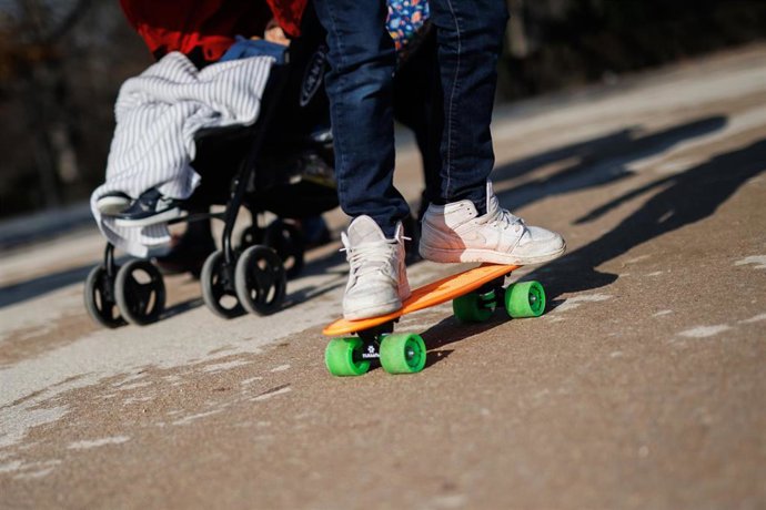 Archivo - Un niño con un patinete pasea por el parque del Retiro.
