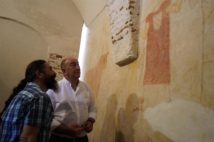 El presidente de la Diputación, Miguel Ángel de Vicente, contempla las pinturas del siglo XIII en la iglesia de Pinarejos con su alcalde, Heliodoro Ríos.