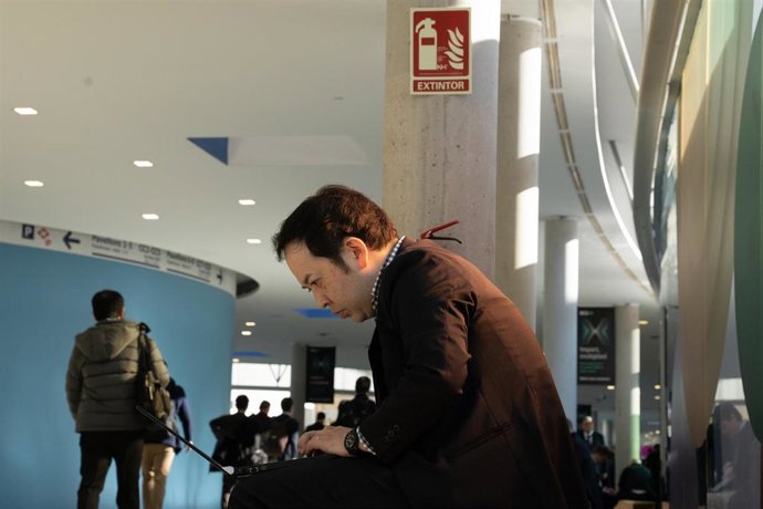 Archivo - Un hombre escribe en su ordenador portátil dentro de las inmediaciones de Fira Barcelona.