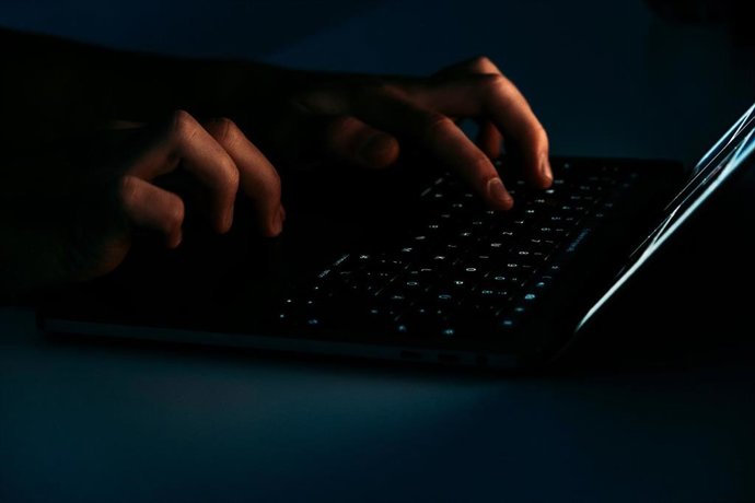 Recurso de persona usando un ordenador portátil en un ambiente oscuro