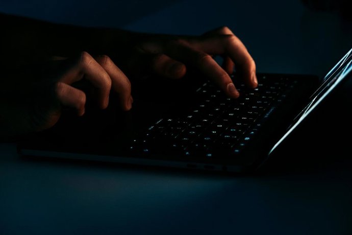 Recurso de persona usando un ordenador portátil en un ambiente oscuro