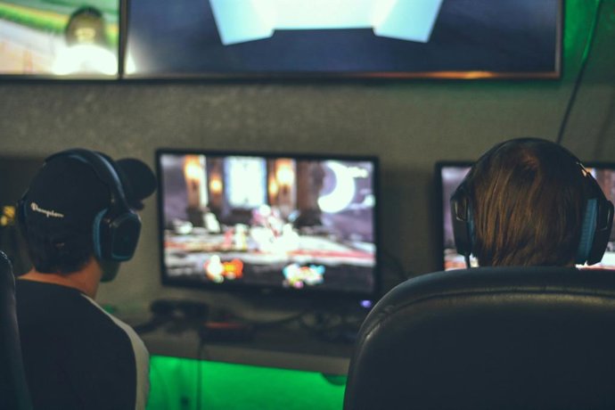 Duas pessoas em frente a uma tela jogando videogame