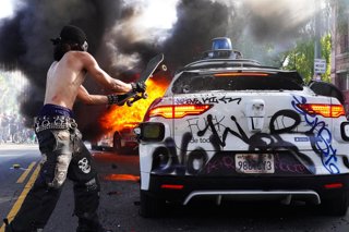 Archivo - June 8, 2025, Los Angeles, California, USA: A protester smashes the back windshield of a car with a skateboard during a protest in downtown Los Angeles, California.