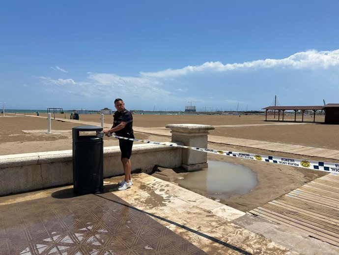 Agente de la Policía Local clausura una playa de València por la alerta de lluvia