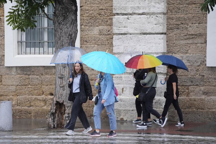 Archivo - Vianants sota paraigües durant la pluja
