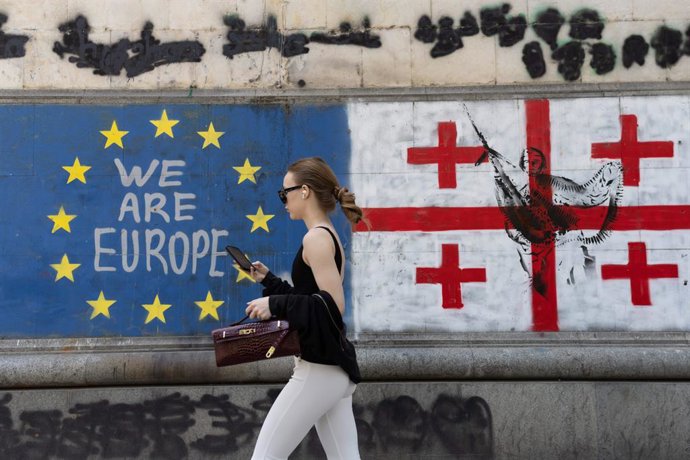 July 7, 2025, Tbilisi, Georgia: A woman walks past the flags of Georgia and the European Union along Shota Rustaveli Avenue near the Freedom Square.